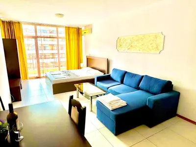 a living room with a blue couch and a table at Grand Kamelia Apartments Sunny Beach in Sunny Beach