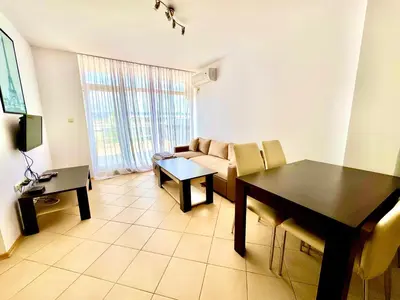 a living room with a table and a couch at Grand Kamelia Apartments Sunny Beach in Sunny Beach