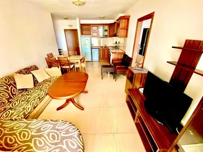 a living room with a couch and a dining room at Grand Kamelia Apartments Sunny Beach in Sunny Beach