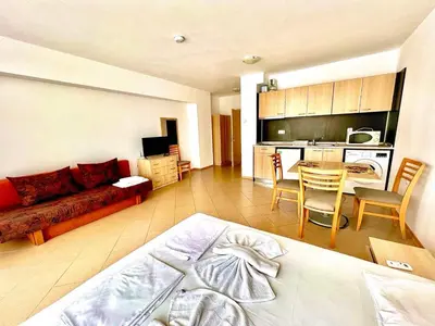a living room with a bed and a kitchen at Grand Kamelia Apartments Sunny Beach in Sunny Beach