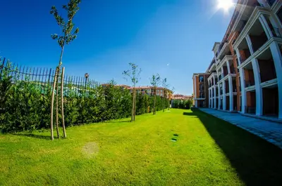 a grassy yard next to a building with a tree at Premier Fort Club Hotel - Full Board in Sunny Beach