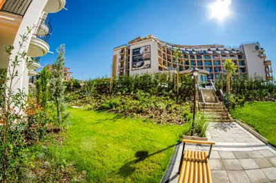 a bench in a garden with a building in the background at Premier Fort Club Hotel - Full Board in Sunny Beach