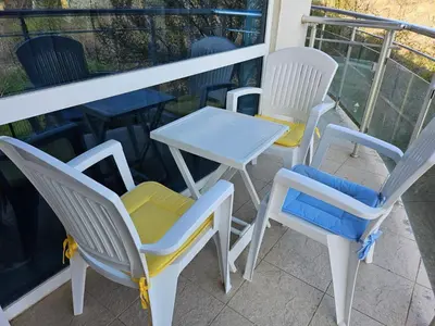 three chairs and a table on a balcony at Студио за двама в Сарафово in Burgas City