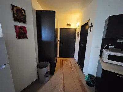 a hallway with two black doors and a microwave at Студио за двама в Сарафово in Burgas City