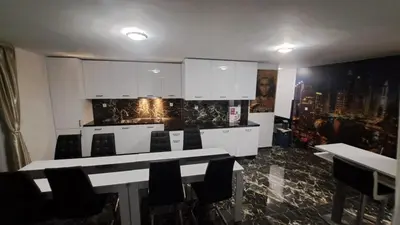 a kitchen with white cabinets and tables and chairs at Luxe 1 Dubai Penthouse in Obzor