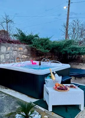 a hot tub in a backyard with a table with food at Вила Лонгоз