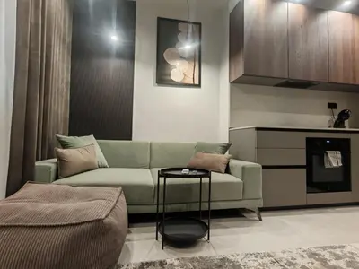 a living room with a green couch and a kitchen at Апартамент Александровска in Burgas City