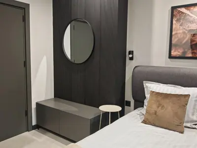 a bedroom with a bed and a mirror and a table at Апартамент Александровска in Burgas City