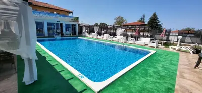 a swimming pool with blue water and white chairs at Complex Exotica in Lozenets