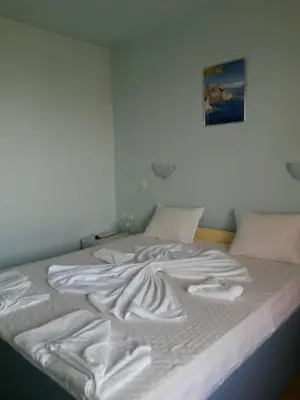 a bed with white sheets and pillows on it at Complex Exotica in Lozenets