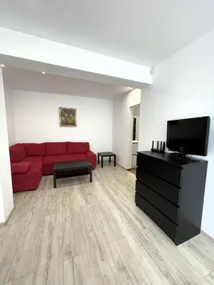a living room with a red couch and a flat screen tv at Velaria Centre Apartment in Burgas City