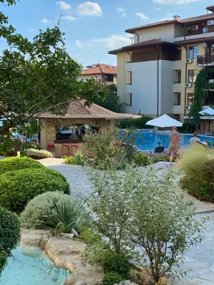 a woman walking by a swimming pool with an umbrella at Garden of Eden - M303 Rey&Mar Apartaments in Sveti Vlas