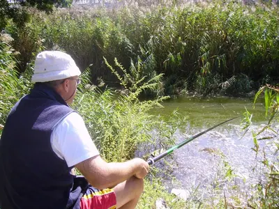 a man holding a fishing rod in a river at Mechta Family Hotel in Obzor