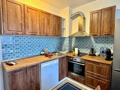 a kitchen with wooden cabinets and a white dishwasher at Galateya in Varna City