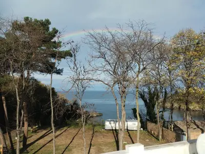 a rainbow in the sky over the water with trees at Sea view in Sozopol