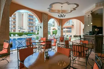 a restaurant with tables and chairs and a chandelier at PALAZZO FAMILY SUITE Sunny beach in Sunny Beach