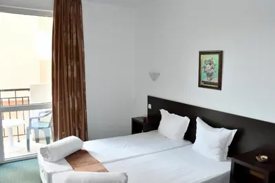 a bedroom with a white bed and a balcony at Family нouse -Нotel Asai in Ravda