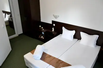 a hotel room with a bed with white sheets and pillows at Family нouse -Нotel Asai in Ravda