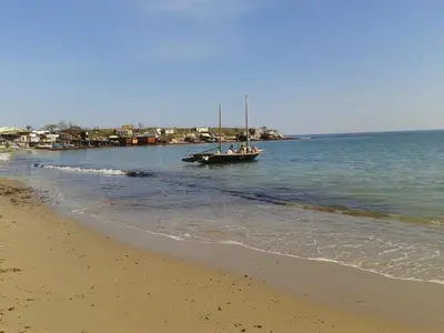 a boat in the water next to a beach at Family нouse -Нotel Asai in Ravda