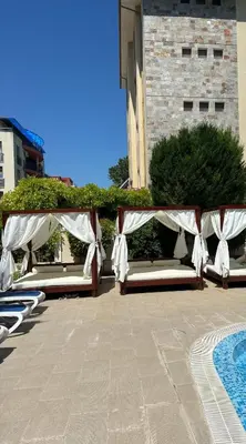 a row of lounge chairs with white curtains on a patio at Villa Valencja Apartments in Sunny Beach