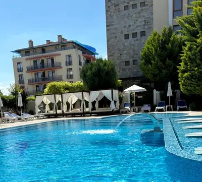 a large swimming pool with chairs and umbrellas at Villa Valencja Apartments in Sunny Beach