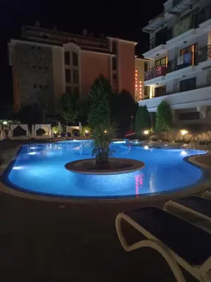 a large pool with a fountain in the middle at night at Villa Valencja Apartments in Sunny Beach