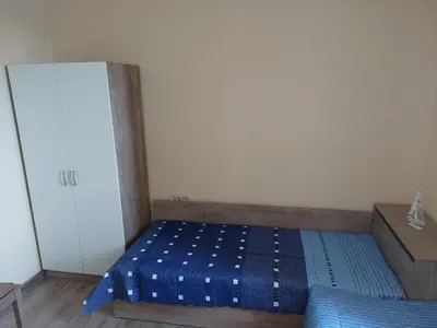 a small bedroom with a blue bed and a cabinet at Апартаменти Делукс 2 in Burgas City