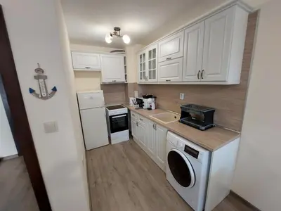 a small kitchen with white cabinets and a washer and dryer at Апартаменти Делукс 2 in Burgas City