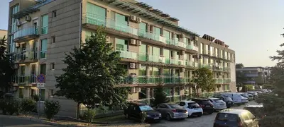 a large building with cars parked in a parking lot at Клара апартамент in Burgas City