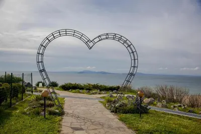 a heart shaped archway on a path near the ocean at Клара апартамент in Burgas City