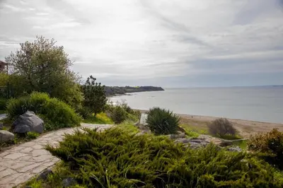 a stone path leading to a beach with the ocean at Клара апартамент in Burgas City