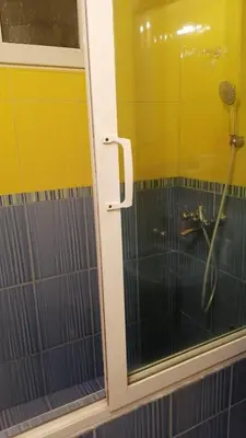 a shower with a glass door in a bathroom at Апартамент опера in Varna City