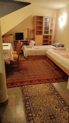 a bedroom with two beds and a desk and a rug at Апартамент опера in Varna City