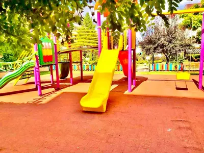 a playground with a yellow slide in a park at Grand Kamelia Holiday Apartments Sunny Beach in Sunny Beach