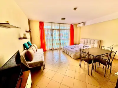 a living room with a bed and a table at Grand Kamelia Holiday Apartments Sunny Beach in Sunny Beach