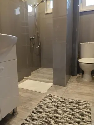 a bathroom with a shower and a toilet and a rug at Guest Rooms Ilko in Varna City