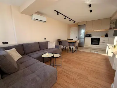 a living room with a gray couch and a kitchen at Seaside Home in Burgas City