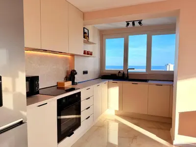 a kitchen with white cabinets and a large window at Seaside Home in Burgas City