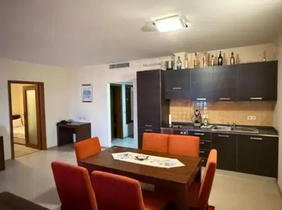 a kitchen with a wooden table and orange chairs at Двуспален апартамент Сънсет ризорт с фронтален изглед към море in Pomorie
