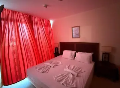 a bedroom with a bed with red curtains at Двуспален апартамент Сънсет ризорт с фронтален изглед към море in Pomorie