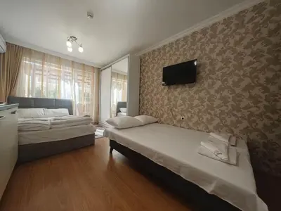 a bedroom with two beds and a tv on the wall at Луксозно Студио Сладък Дом в Слънчев бряг in Sunny Beach