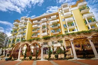 a yellow building with white balconies and plants at Луксозно Студио Сладък Дом в Слънчев бряг in Sunny Beach