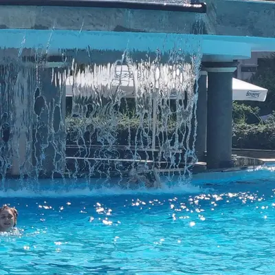 a person swimming in a pool with a fountain at Emerald Beach Resort & Spa, Apartment S105 in Ravda