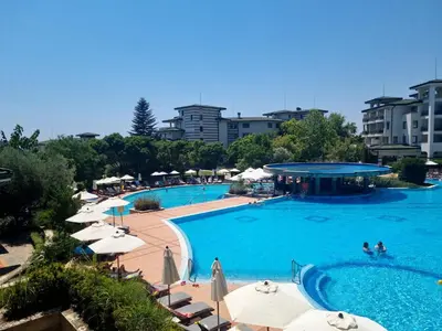 a large swimming pool with umbrellas and people in it at Emerald Beach Resort & Spa, Apartment S105 in Ravda