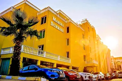 a yellow building with cars parked in front of it at Marina Sunrise Complex by the sea in Sveti Vlas