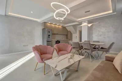 a living room with a table and pink chairs at Central Luxury One Bedroom in Varna in Varna City
