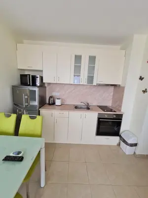 a kitchen with white cabinets and yellow chairs in it at Studio in a Resort with 9 pools in Sunny Beach