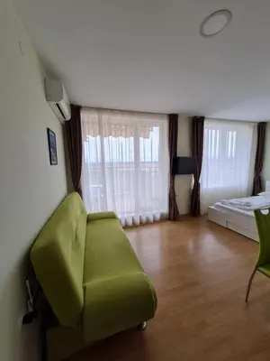 a living room with a green couch and a bed at Studio in a Resort with 9 pools in Sunny Beach