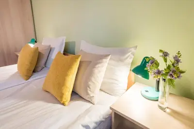 a bed with white pillows and a vase of flowers on a table at Calm space in Varna top center in Varna City