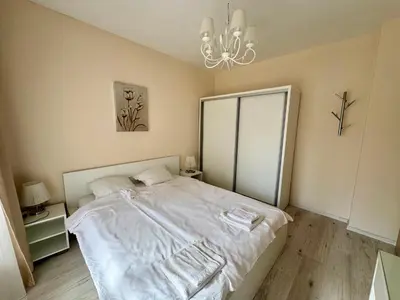 a bedroom with a white bed and a chandelier at Above the Sea Luxury Apartment in Varna City